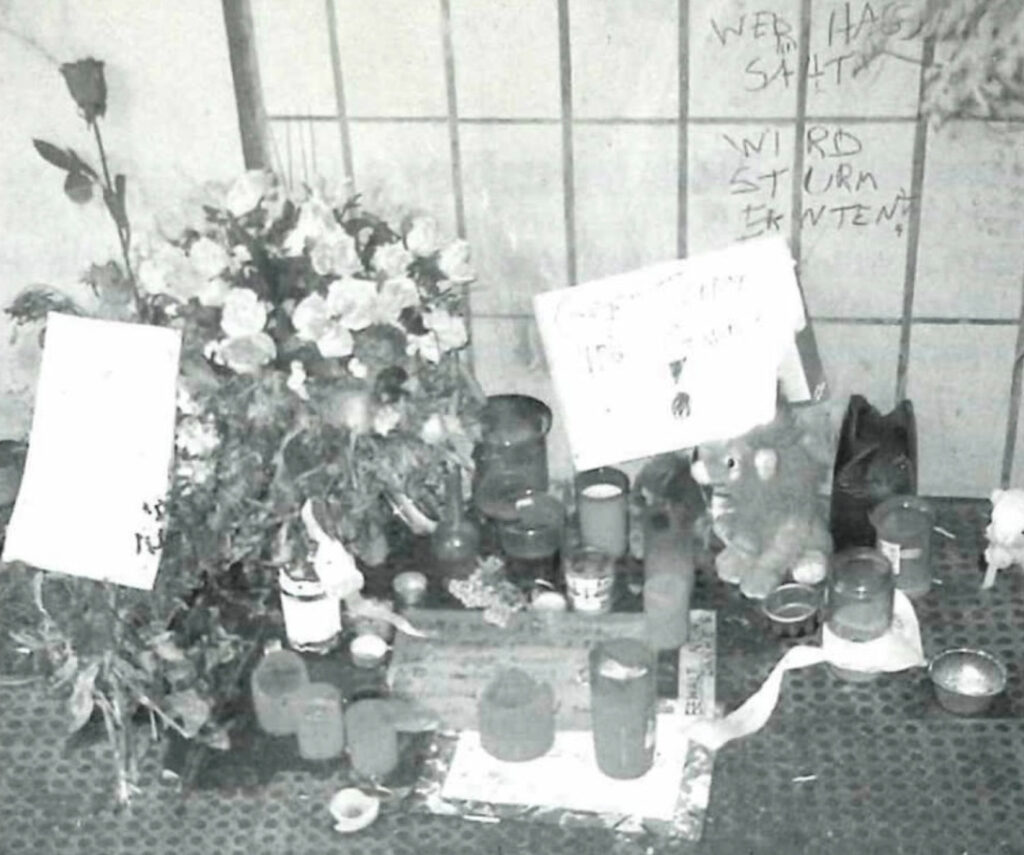 Juli/August 2000: Wochenlang werden Blumen, Kerzen, Stofftiere, Kinderbriefe, mitfühlende Nachrichten und weitere individuelle Erinnerungszeichen an der Anschlagstelle abgelegt. (Foto: Searchlight, September 2000)